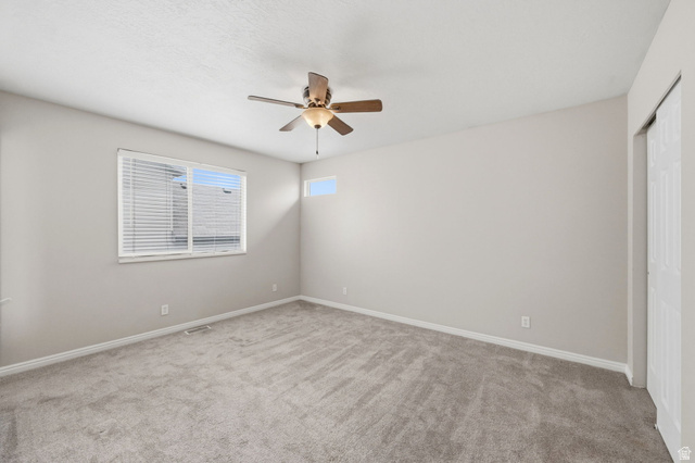 2575 Athena Drive Magna, UT 84044 - Photo 10 of 23 Carpeted room featuring a ceiling fan with integrated lighting, a large horizontal window with blinds, a high transom window, and white bi-fold closet doors