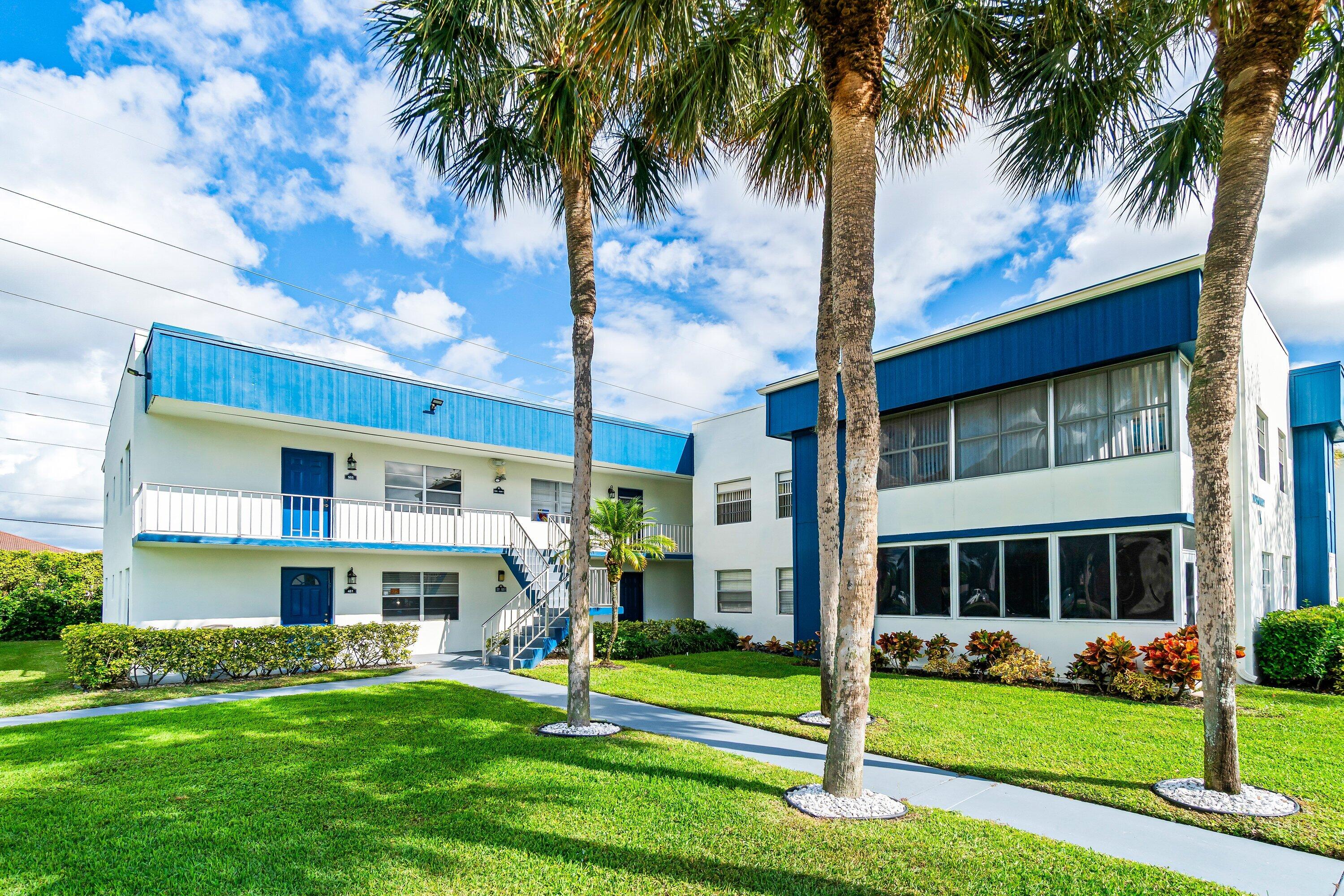 508 Normandy Lane, Unit 508 Delray Beach, FL 33484 - Photo 2 of 25 a front view of a building with a garden and trees