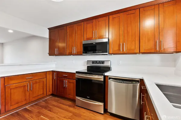 a kitchen with granite countertop wood cabinets stainless steel appliances and a sink