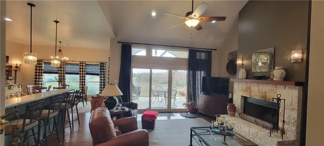 a living room with furniture a fireplace and floor to ceiling windows