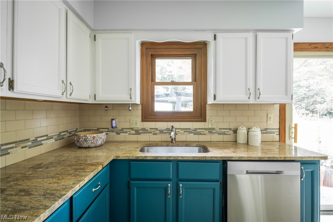 868 Trebisky Road Cleveland, OH 44121 - Photo 8 of 35 Kitchen with stainless steel dishwasher, white cabinetry, granite counters and backsplash