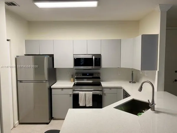 a kitchen with a refrigerator sink and white cabinets