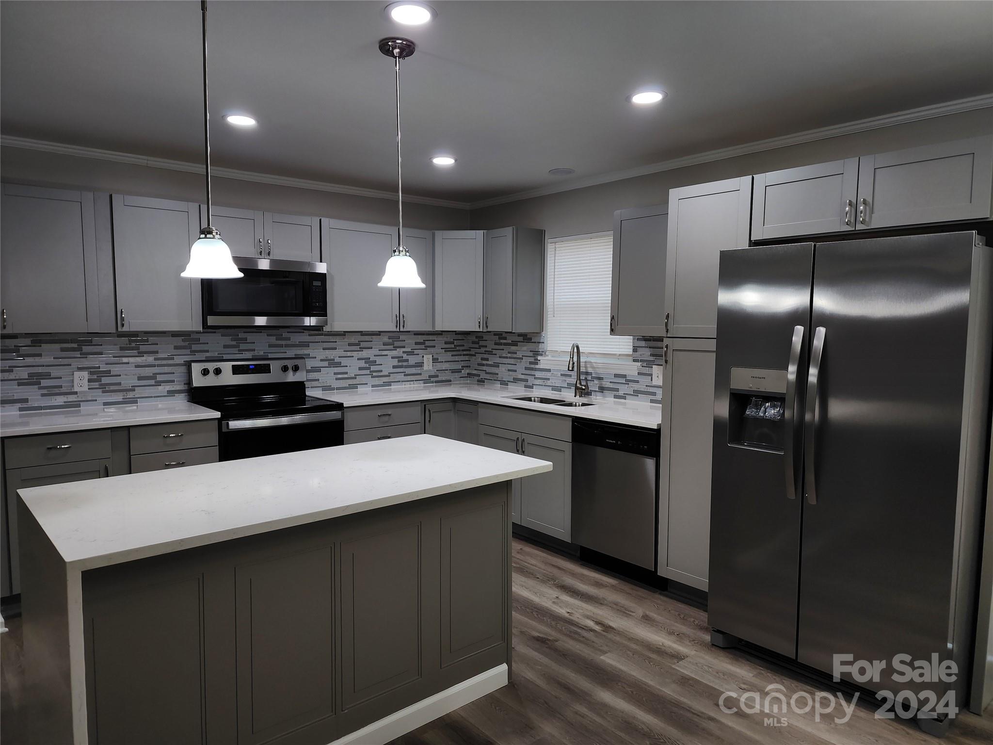 a kitchen with stainless steel appliances kitchen island granite countertop a refrigerator a sink a stove a microwave a counter space and cabinets