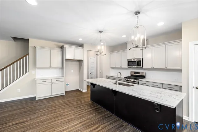 a kitchen with granite countertop a sink appliances cabinets and wooden floor