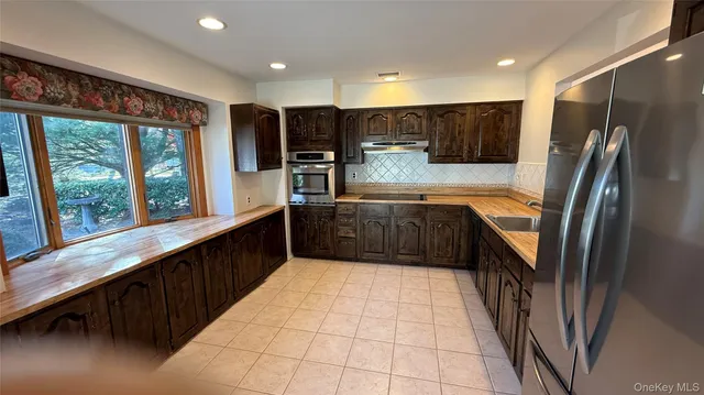 a large kitchen with stainless steel appliances granite countertop a refrigerator and a sink