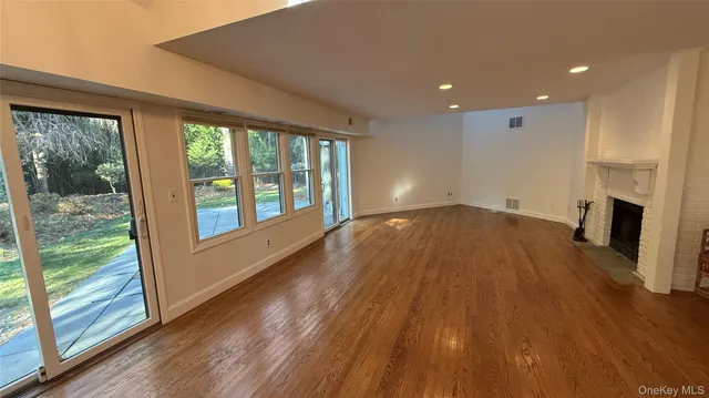 a view of empty room with wooden floor and fireplace