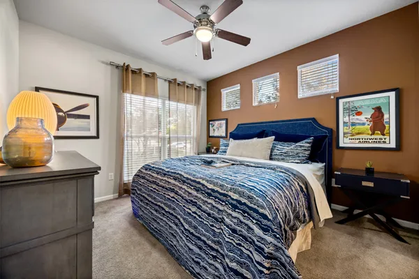 a bedroom with a bed and dresser with wooden floor