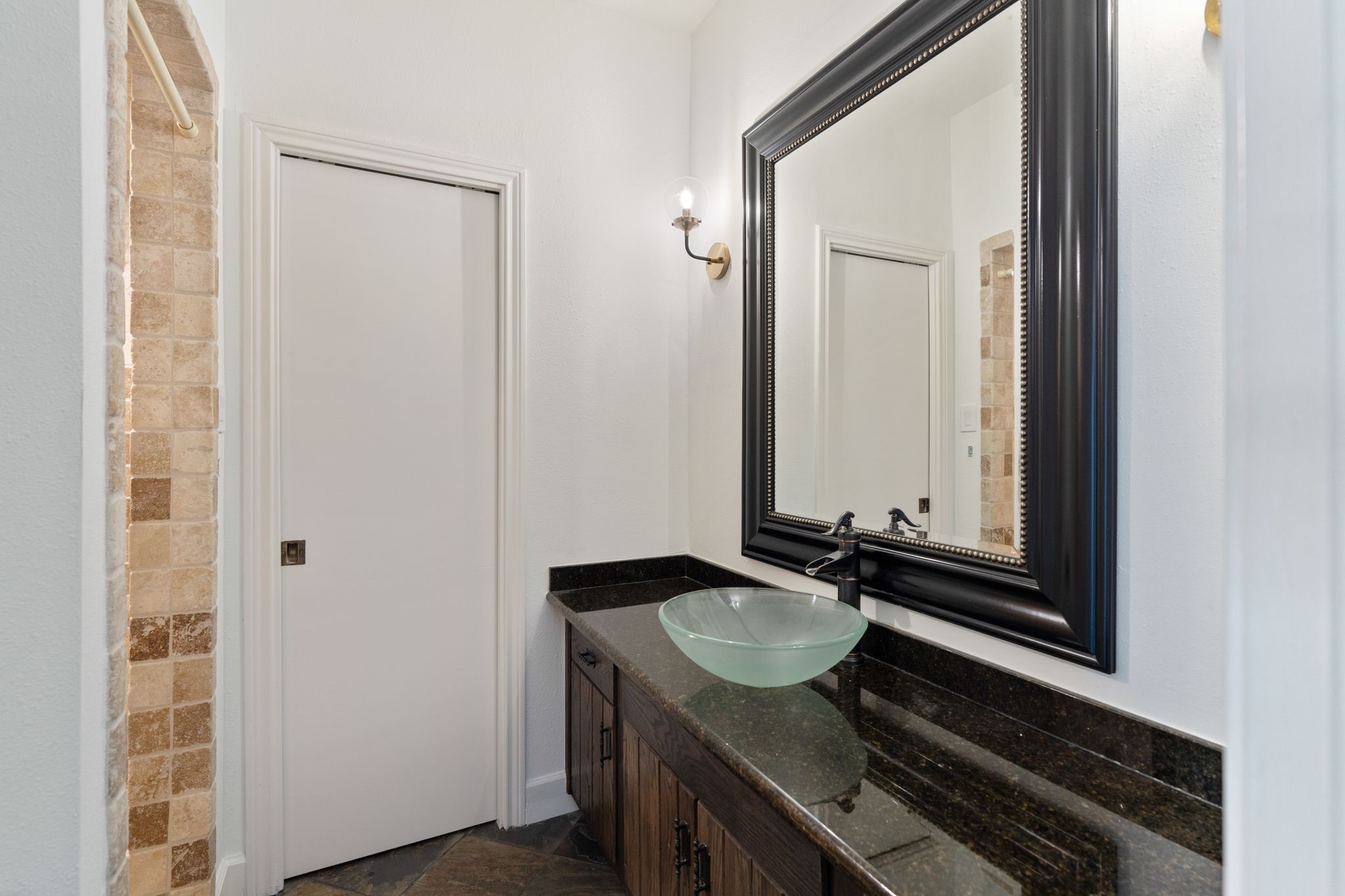153 Sage Road Houston, TX 77056 - Photo 27 of 36 Conveniently accessible from the second bedroom #2 and game room, the guest bath features a granite-topped vanity, glass vessel sink, updated lighting and a walk-in shower with tile surround. The pocket door opens to linen storage.