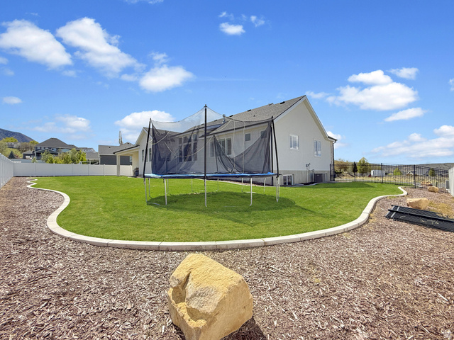 916 Rocky Mountain Way Elk Ridge, UT 84651 - Photo 51 of 54 Rear view of house with a trampoline and a fenced backyard