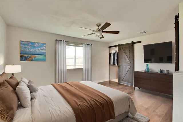 a bedroom with a bed a flat screen tv and a chandelier