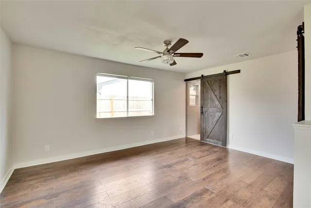 a view of empty room with wooden floor and fan