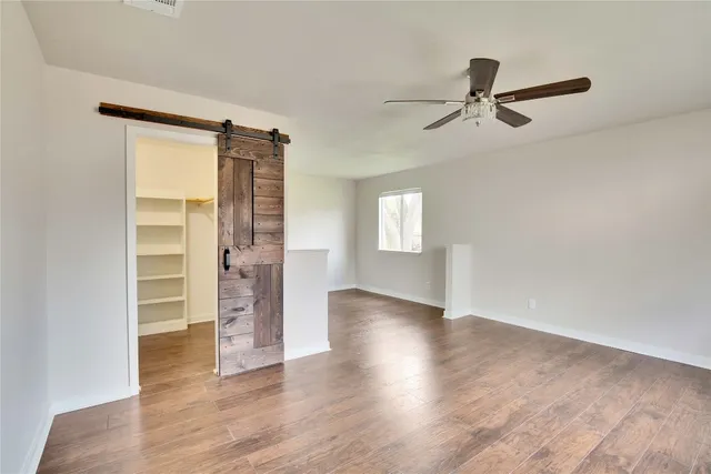 an empty room with wooden floor closet and windows