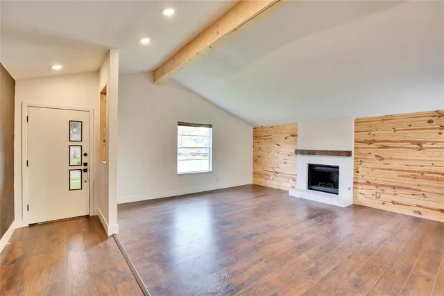 an empty room with wooden floor a fireplace and windows