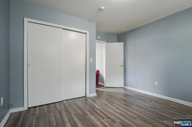 a view of an empty room with wooden floor and closet