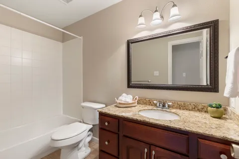 a bathroom with a granite countertop sink vanity mirror and toilet