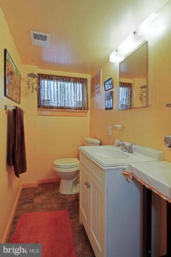 5628 Heming Avenue Springfield, VA 22151 - Photo 14 of 30 a bathroom with a granite countertop sink a toilet and a mirror
