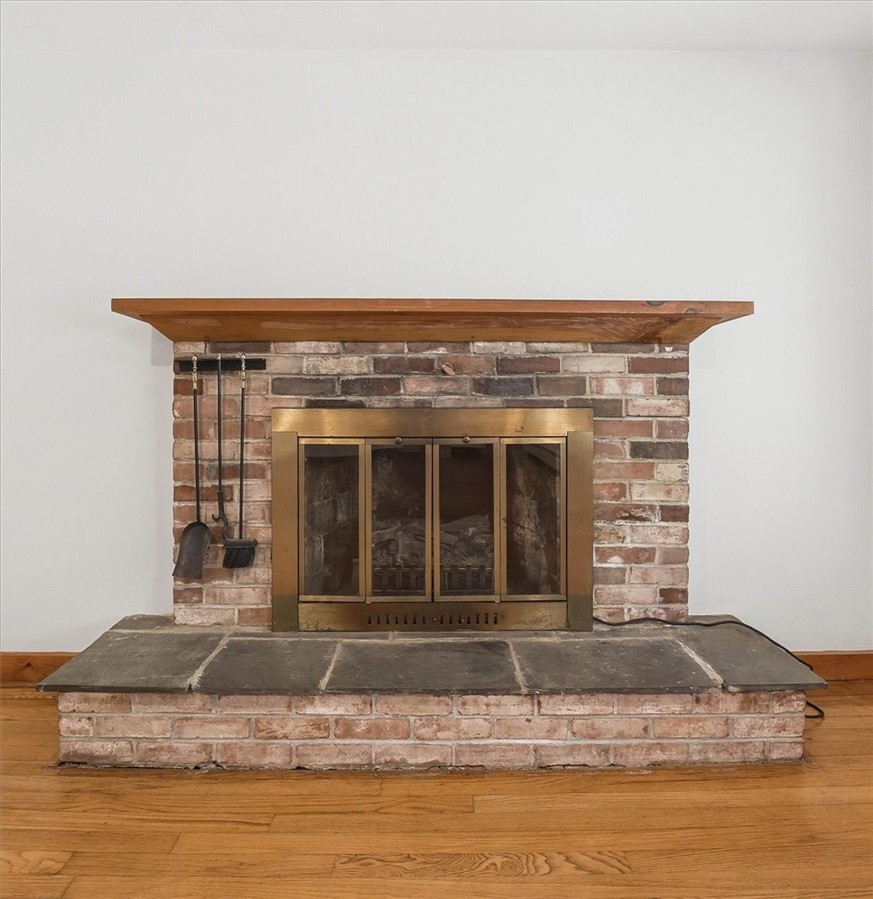 322 Rocky Hill Road Scituate, RI 02857 - Photo 16 of 50 Classic brick fireplace with raised hearth and wood mantel creates a timeless focal point in the living room—perfect for cozy evenings and adding character to the space.