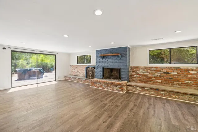 a view of an empty room with fire place and wooden floor