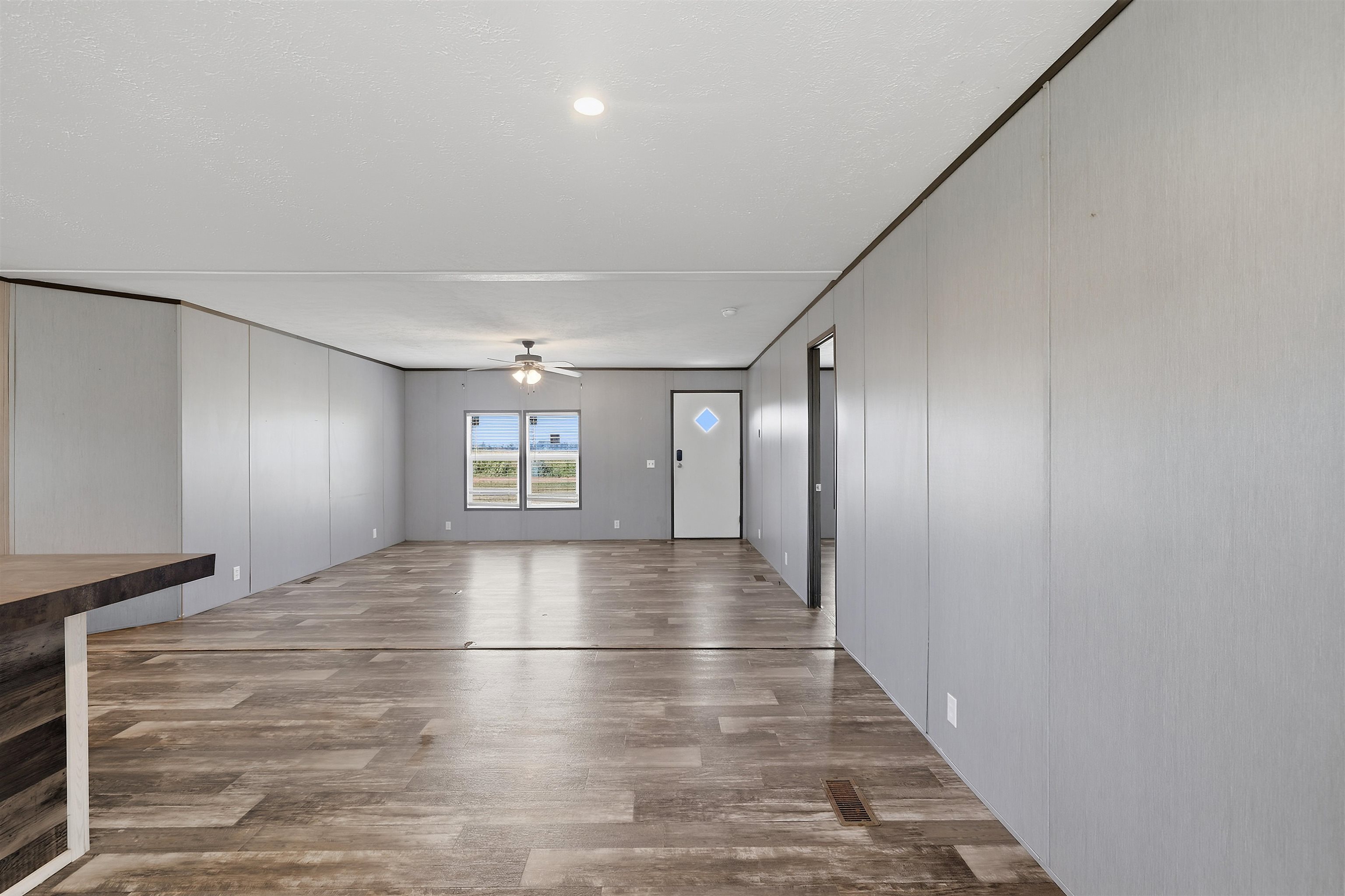 664 Rialto Road Covington, TN 38019 - Photo 8 of 24 Spacious interior featuring wood-finish flooring, two large windows, a ceiling fan, and panel walls