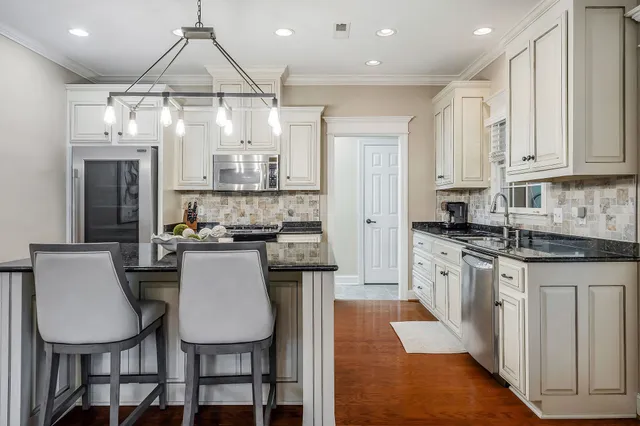 a kitchen with stainless steel appliances a dining table chairs and a refrigerator
