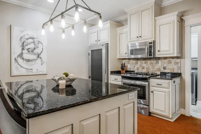 a kitchen with granite countertop white cabinets and refrigerator