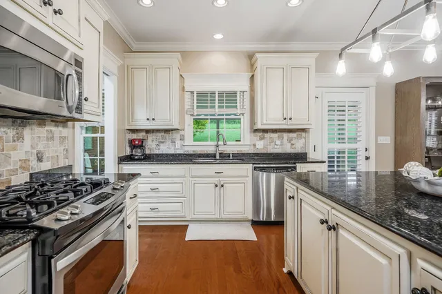 a kitchen with stainless steel appliances granite countertop a stove sink and cabinets