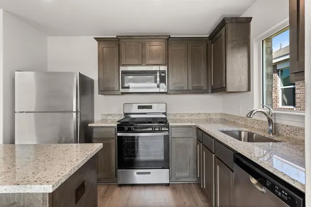 a kitchen with granite countertop a sink stove and refrigerator