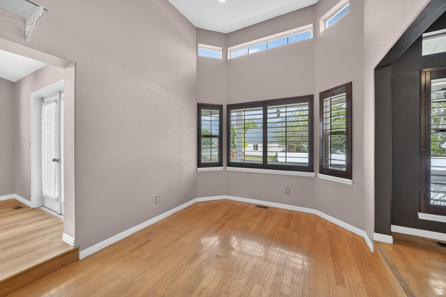1464 990 West Provo, UT 84601 - Photo 5 of 41 Interior space featuring light wood-finish flooring, high ceilings, and a bay window configuration with dark wood trim and horizontal blinds