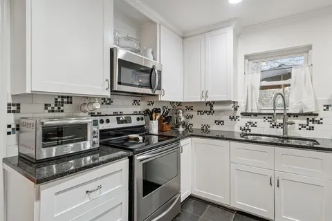 a kitchen with granite countertop white cabinets and appliances