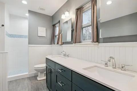 a bathroom with a double vanity sink toilet and a mirror
