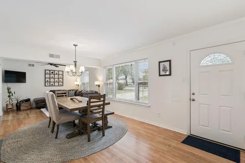 a dining room with wooden floor a chandelier a wooden table and chairs