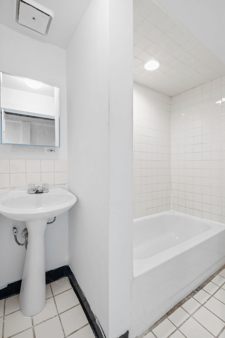 7518 South Rhodes Avenue Chicago, IL 60619 - Photo 11 of 12 a bathroom with a sink a mirror and a bathtub