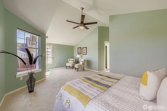 a bedroom with a bed a couch and potted plant on the dresser