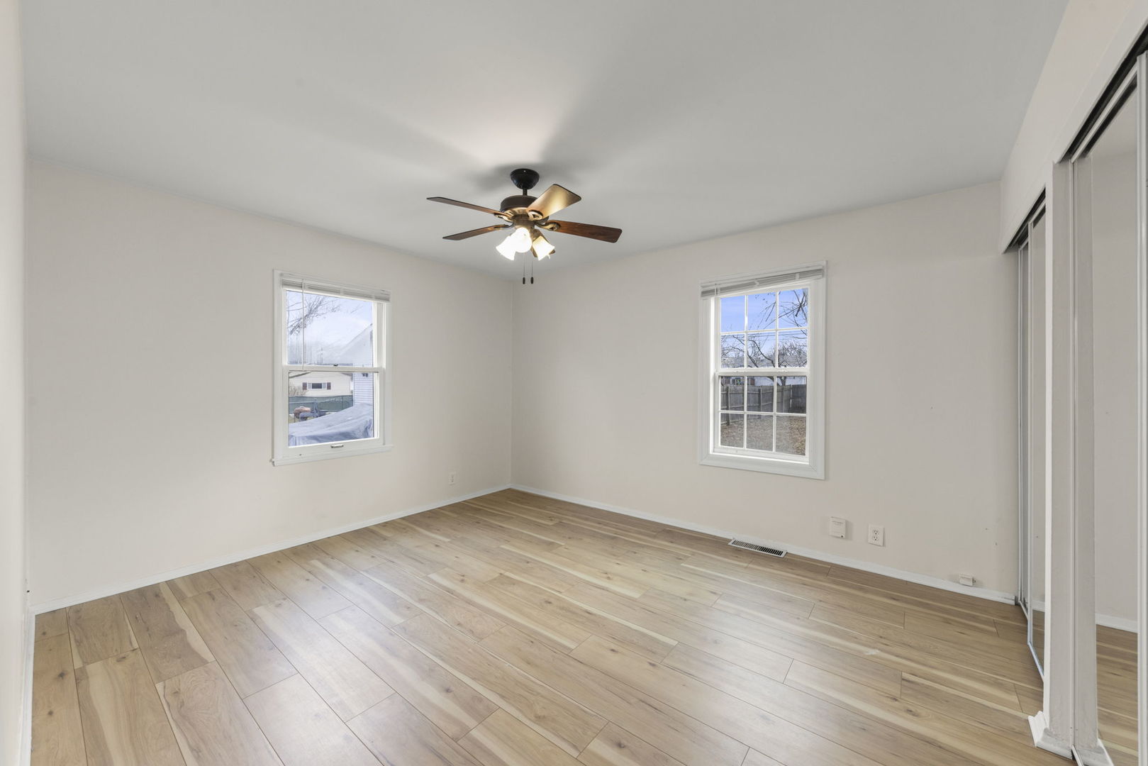 422 Best Avenue DeKalb, IL 60115 - Photo 13 of 34 an empty room with wooden floor chandelier fan and windows
