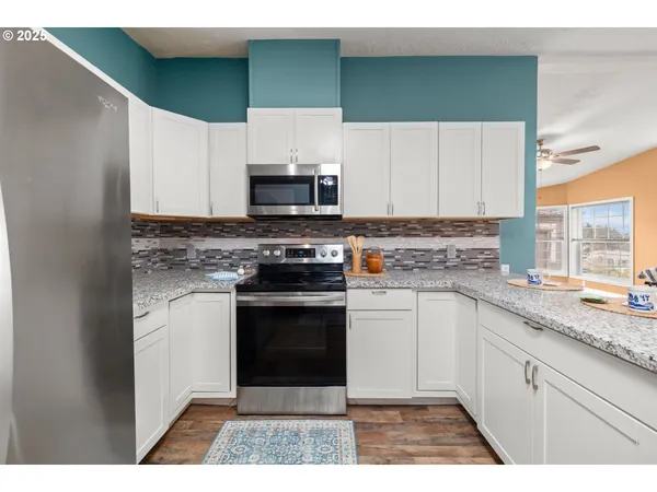 a kitchen with stainless steel appliances granite countertop a stove a sink and a microwave