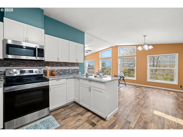 a kitchen with granite countertop a stove a sink and a microwave