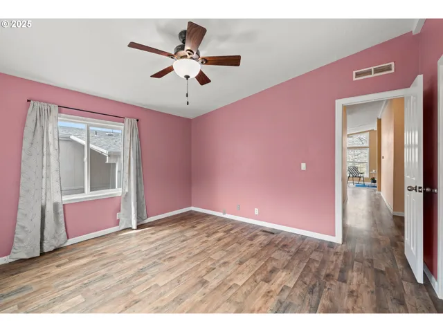 a view of an empty room with window and wooden floor