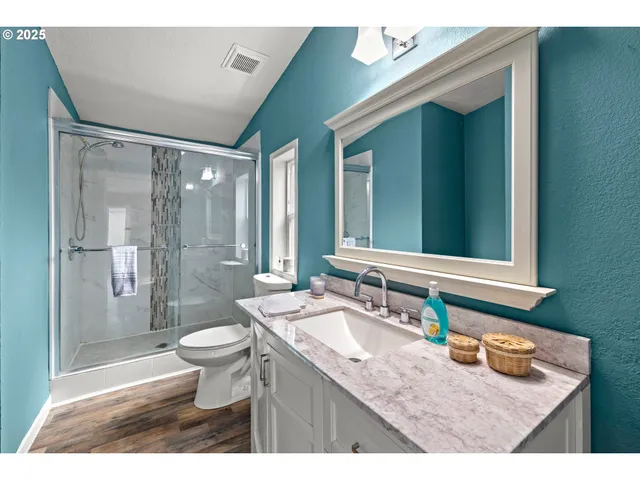 a bathroom with a granite countertop sink toilet mirror and shower