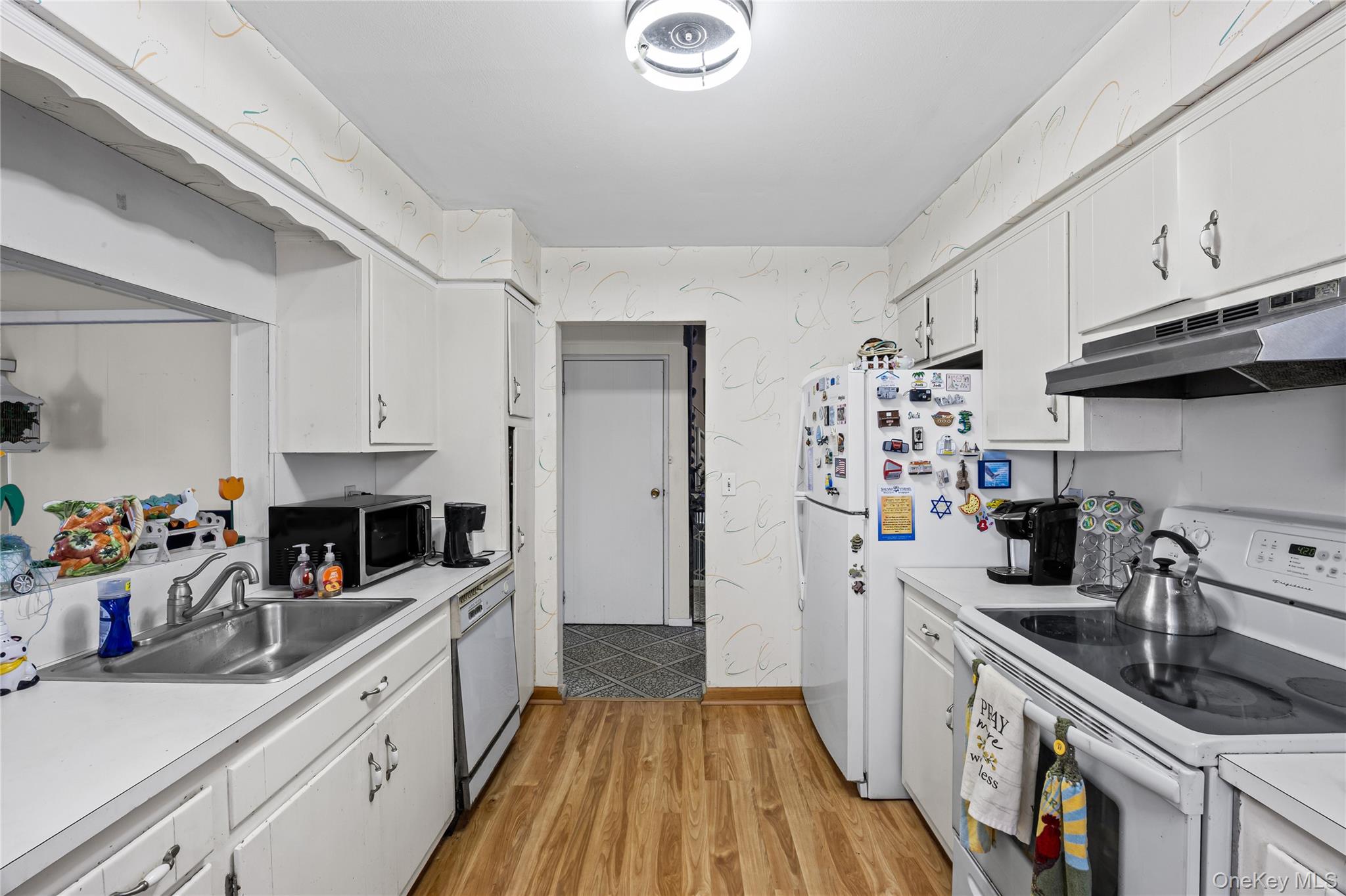 2929 Mandalay Beach Road Wantagh, NY 11793 - Photo 7 of 26 a kitchen with granite countertop a refrigerator a sink dishwasher stove and white cabinets with wooden floor