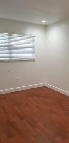 en empty room with wooden floor and windows