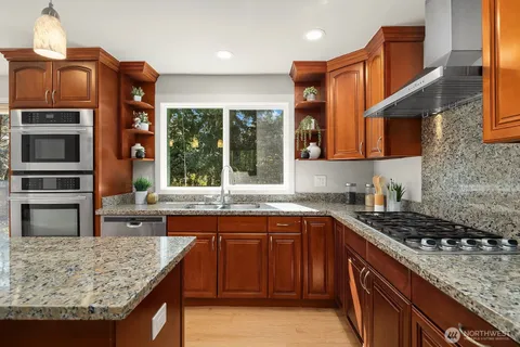 a kitchen with stainless steel appliances granite countertop a stove a sink and a microwave