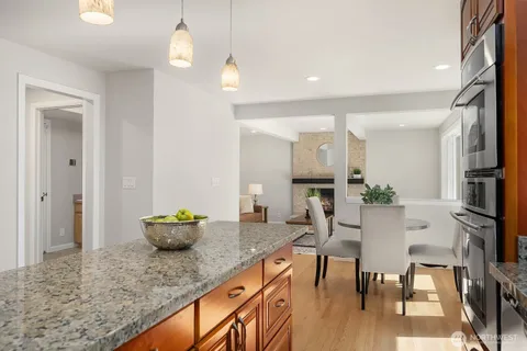 a dining room with stainless steel appliances kitchen island granite countertop a table chairs and a refrigerator