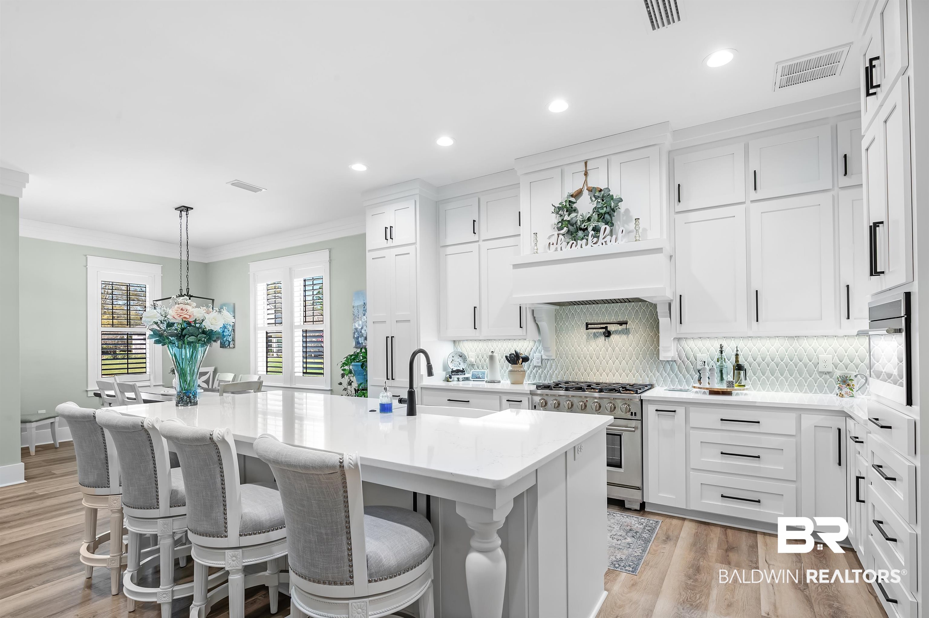 9144 Harvest Ridge Fairhope, AL 36532 - Photo 23 of 58 Kitchen with visible vents, ornamental molding, stainless steel appliances, white cabinetry, and an island with sink