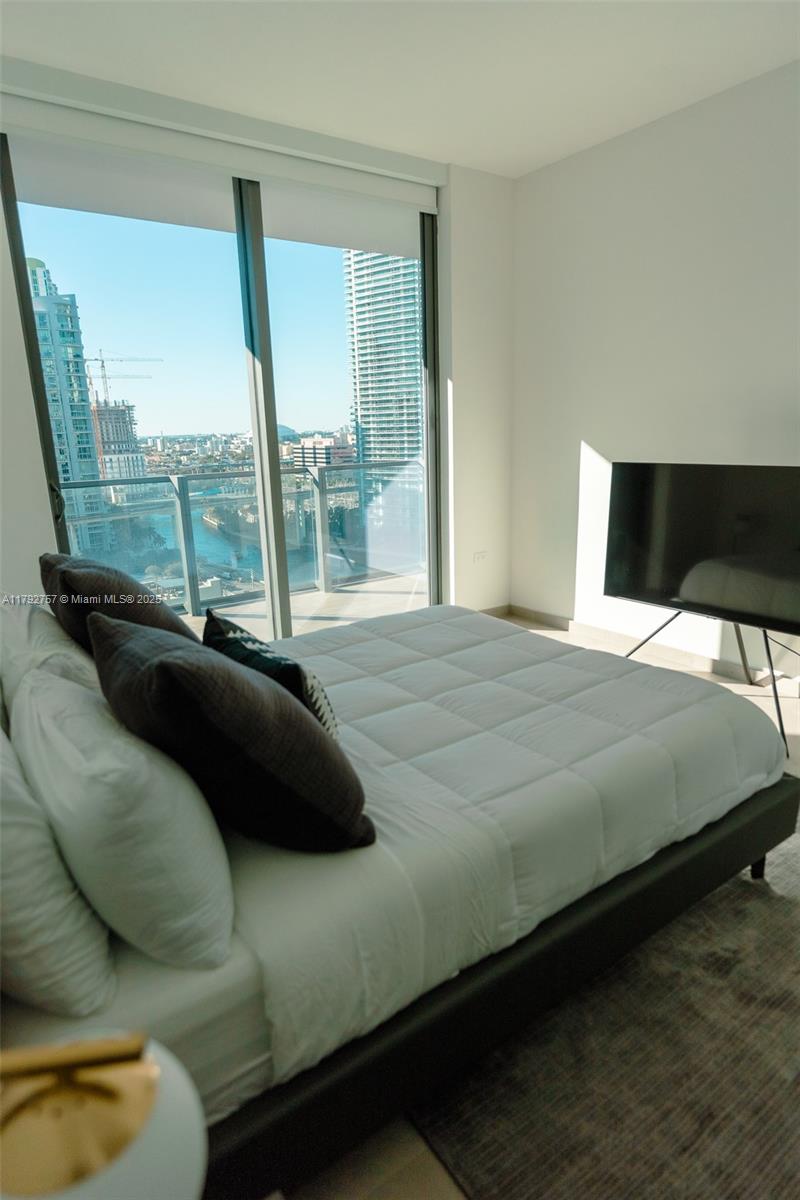 68 Southeast 6th Street, Unit 1204 Miami, FL 33131 - Photo 13 of 48 a bedroom with a bed and glass window