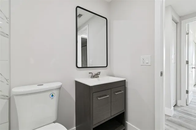 a bathroom with a toilet sink vanity and mirror