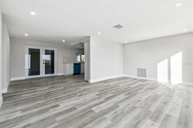 a view of an empty room with wooden floor and windows