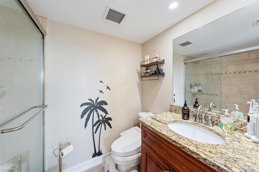 190 Pebble Beach Boulevard, Unit 502 Naples, FL 34113 - Photo 18 of 27 a bathroom with a granite countertop toilet a sink and a mirror