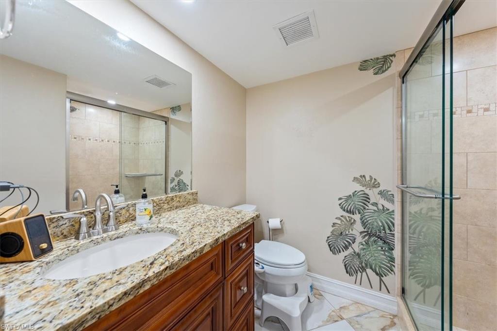 190 Pebble Beach Boulevard, Unit 502 Naples, FL 34113 - Photo 20 of 27 a bathroom with a granite countertop sink a toilet a mirror and shower