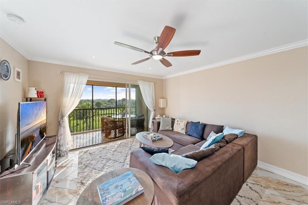 190 Pebble Beach Boulevard, Unit 502 Naples, FL 34113 - Photo 6 of 27 a living room with furniture a flat screen tv and a floor to ceiling window