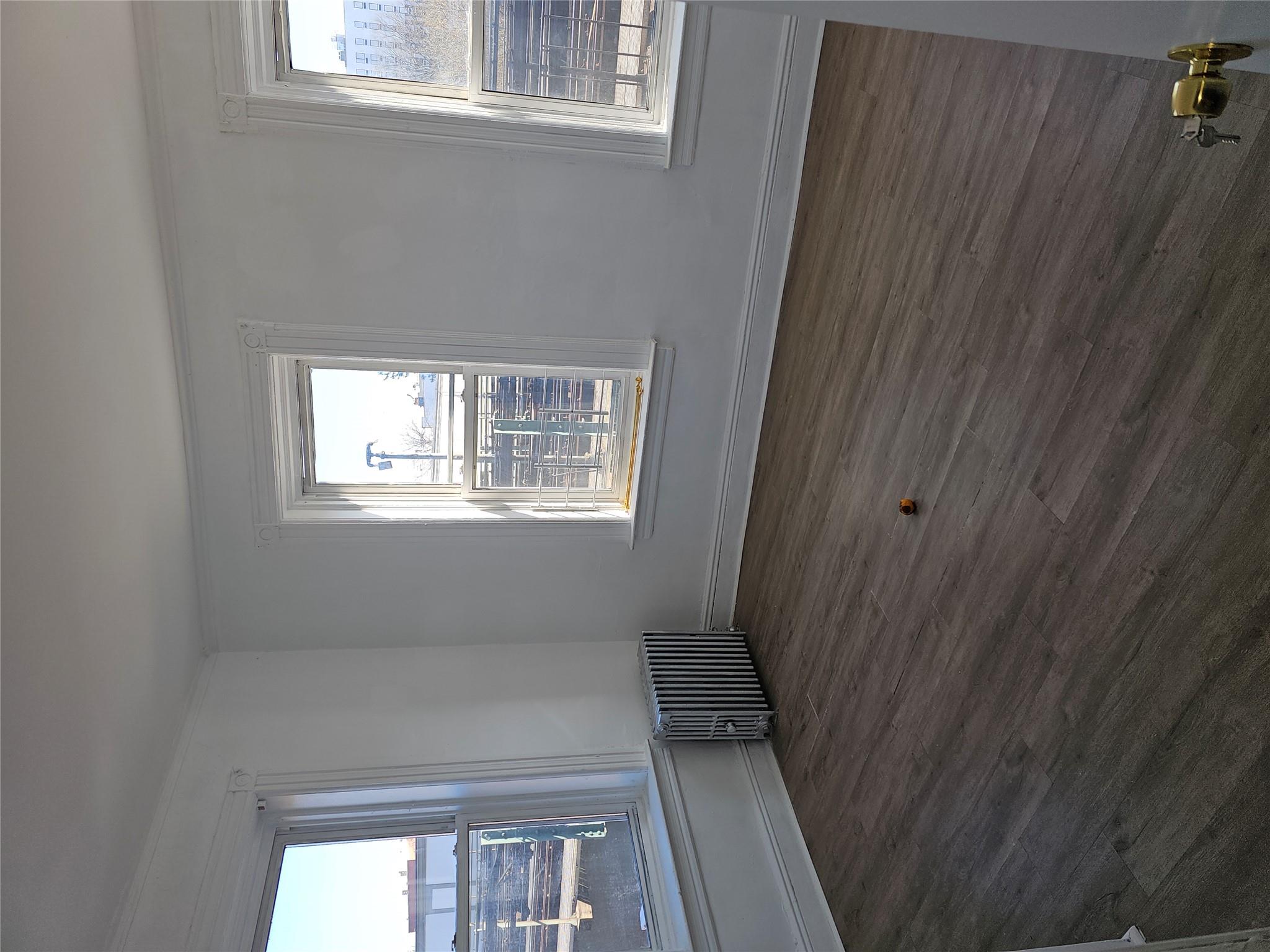 Empty room with dark wood finished floors, crown molding, radiator heating unit, and baseboards